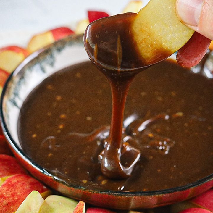 Healthier Caramel Apple dip with apple slice dipping into caramel
