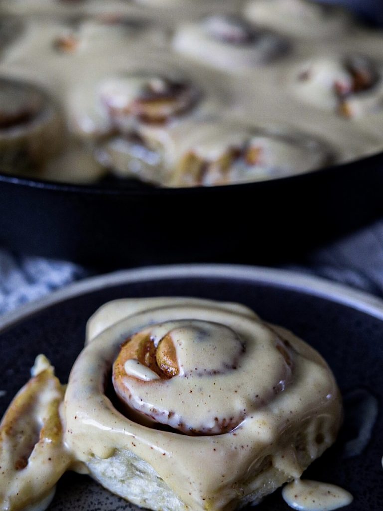 fluffy sourdough cinnamon rolls on plate with cream cheese frosting