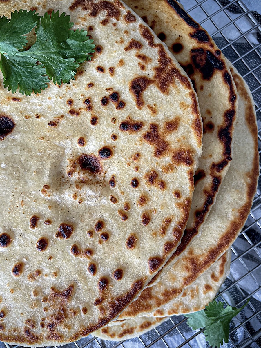 easy buttery sourdough naan bread stacked on wire rack