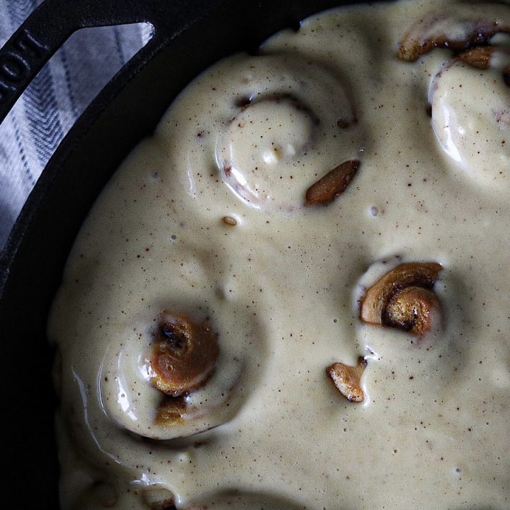 fluffy sourdough cinnamon rolls in skillet with cream cheese frosting