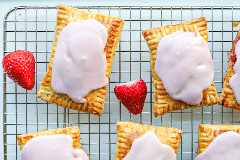 Easy homemade sourdough pop tarts on wire rack with strawberries and pink icing simple is gourmet