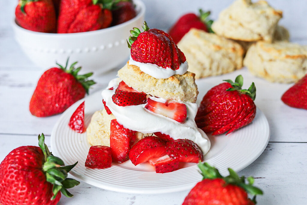 Quick Strawberry Shortcake Made with Biscuits on white plate with surrounding strawberries